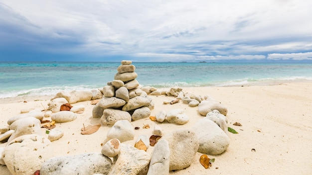 Balanced pebbles pyramid on beach on cloudy day and blue sea. Dramatic energy vibes zen concept