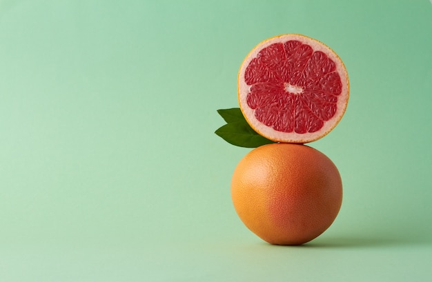 Balancing grapefruit on green background copy space