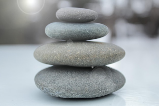 Balancing stones against the backdrop of winter nature under bright sunlight.