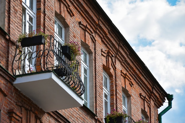 Balcony with flowers on an old brick building in the historic center of the city