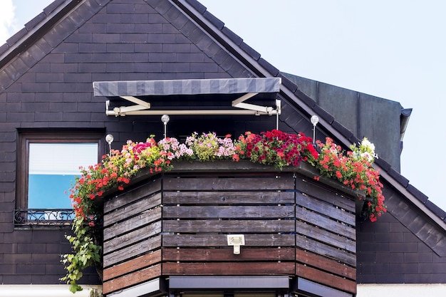 Balcony with Flowers. Wooden Balcony Railings and textile Canopy on Facade of wooden House.