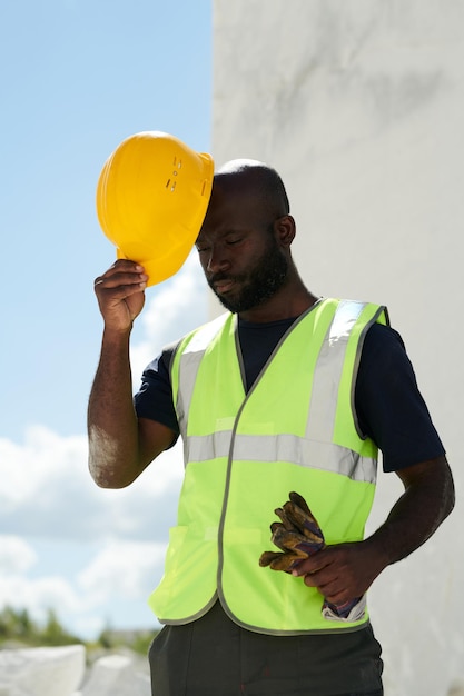 Bald african american engineer in uniform putting safety helmet on his head