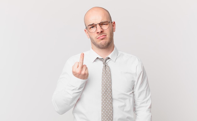 Bald businessman feeling angry, annoyed, rebellious and aggressive, flipping the middle finger, fighting back