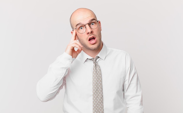 Bald businessman looking surprised, open-mouthed, shocked, realizing a new thought, idea or concept