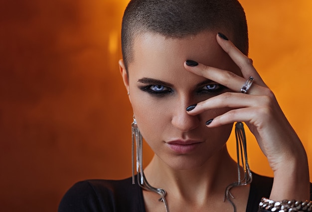 Bald girl, wet face, hand rings, cheeky girl, orange background, biting fingers