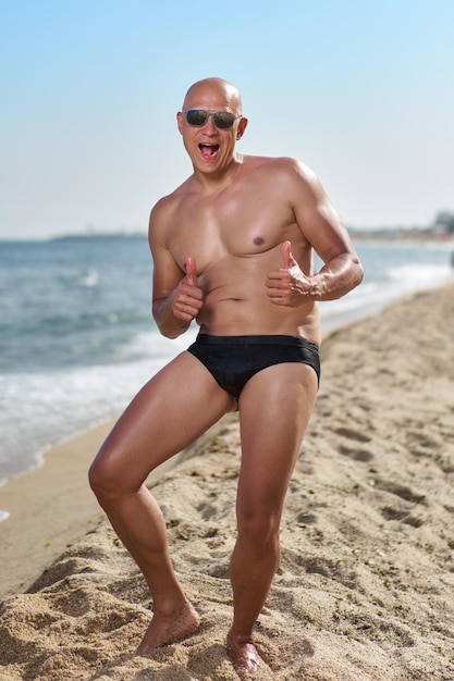 Bald man on the beach by the sea on vacation