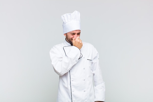 Bald man feeling disgusted, holding nose to avoid smelling a foul and unpleasant stench