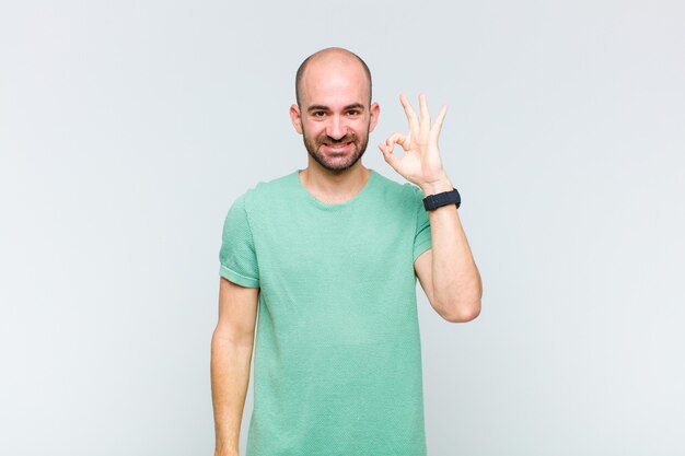 Bald man feeling happy, relaxed and satisfied, showing approval with okay gesture, smiling