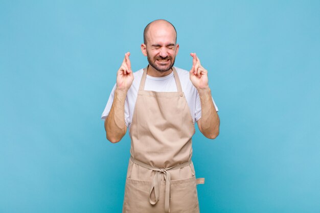 Bald man feeling nervous and hopeful, crossing fingers, praying and hoping for good luck