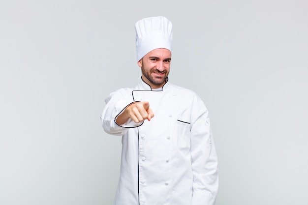 Bald man pointing at camera with a satisfied, confident, friendly smile, choosing you