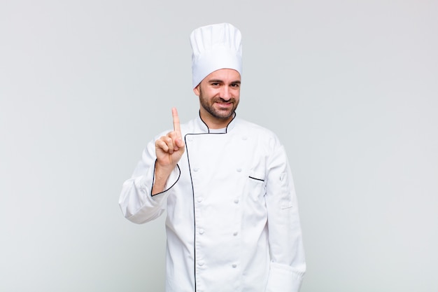 Bald man smiling and looking friendly, showing number one or first with hand forward, counting down