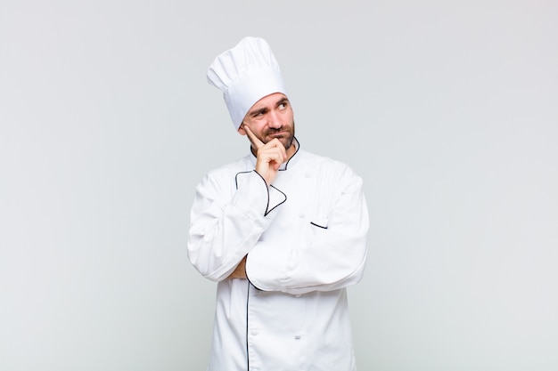 Bald man with a concentrated look, wondering with a doubtful expression, looking up and to the side