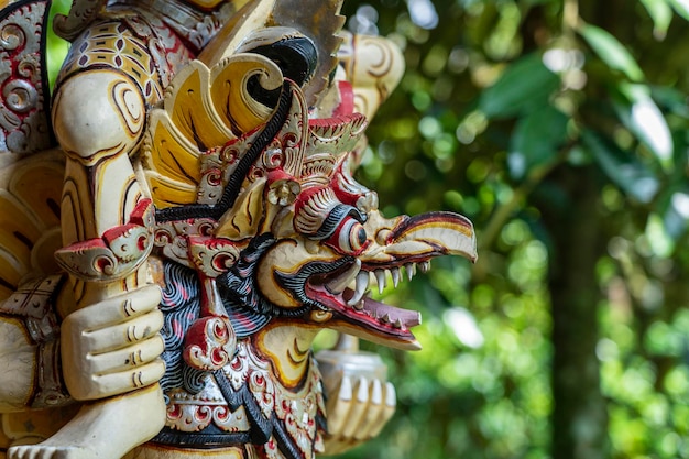 Balinese ancient colorful bird god Garuda with wings closeup Religious traditional statue from wood Wooden old curved figure of Hindu god in Island Bali Ubud Indonesia