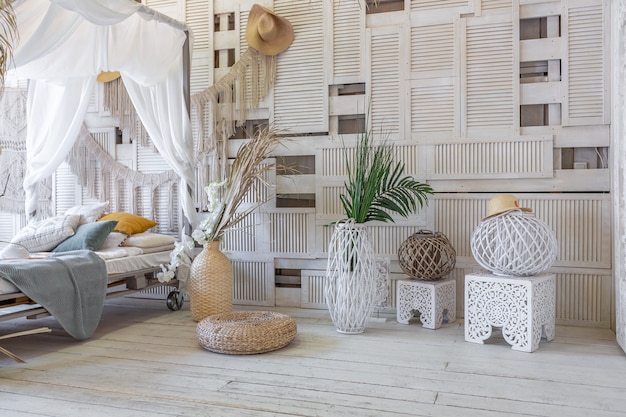 Balinese style bedroom interior. canopy bed with lots of textiles for decoration and wicker items in soft pastel colors