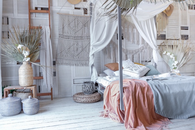 Balinese style bedroom interior. canopy bed with lots of textiles for decoration and wicker items in soft pastel colors