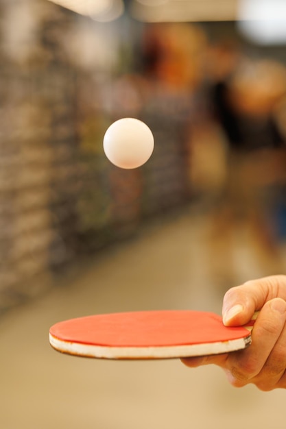 A ball in flight over a table tennis racket in the player's hand