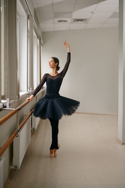 Ballerina doing exercise at barre in class. Ballet training, dance studio interior