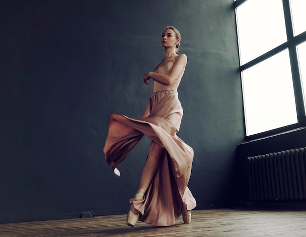 Ballerina in a pink dress and punts moves around the room with a fluttering dress