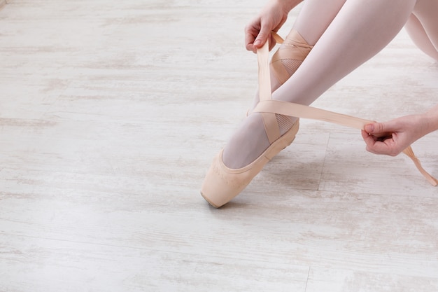 Ballerina puts on pointe ballet shoes