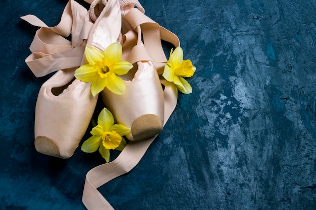 Ballerina shoes, Pointe shoes without people on a blue background. Flowers of yellow daffodil.