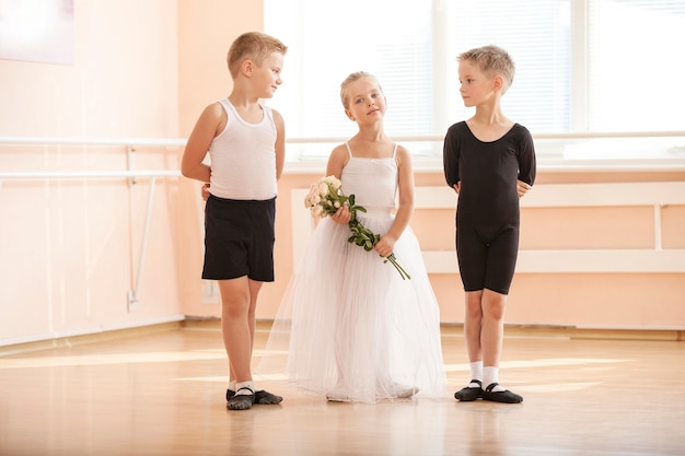 At ballet dancing class: young boys and a girl with flowers posing gracefully