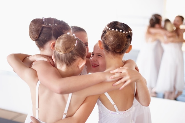 Ballet friends and hug or girl children smile and fun at dance studio or learn together Happy embrace and students in training or group celebrate at academy and young ballerinas or friendship