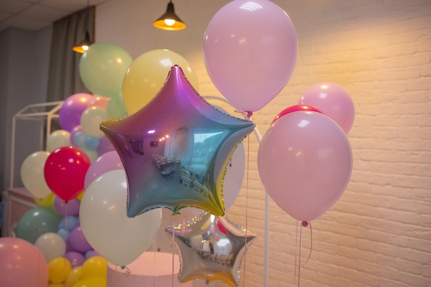 Balloons are attached to the railing of the porch. Opening of the store. Cream wall, red staircase. Bright sunlight and shadows. Festive street background.