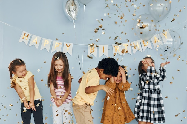 Balloons and confetti Children on celebrating birthday party indoors have fun together