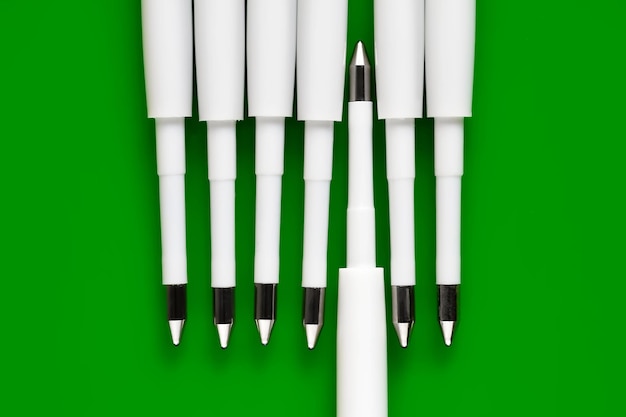 Photo ballpoint pen refills plastic rods for a ballpoint pen row of white ink refills on a green