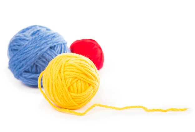 Balls of blue, red and yellow woolen threads on the white background