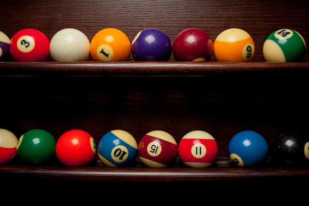 Balls for pool billiards on the shelf , billiard balls for American billiards , balls for Russian billiards , colored or white balls for billiards on a wooden background. Close-up photo. Soft focus.