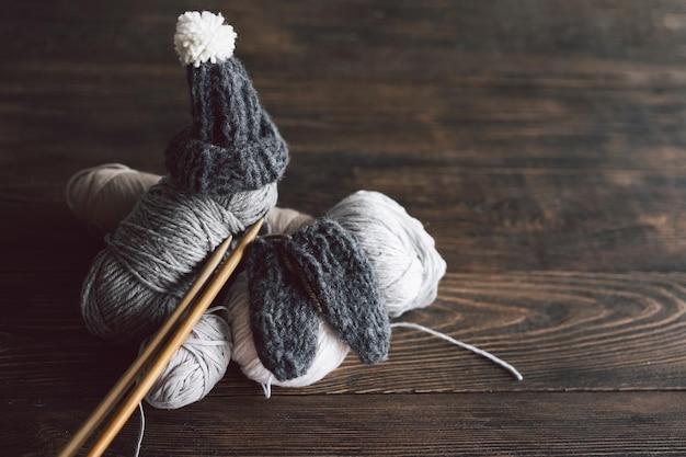 Balls of wool yarn knitted little hat and wooden knitting needles on wooden background Hobby craft Concept of knitting needlework