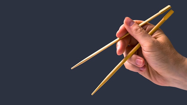 Bamboo chopsticks in a male hand on a dark background items for food