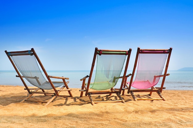 Bamboo deck chairs on the sandy beach with bright sun and waves island south of thailand