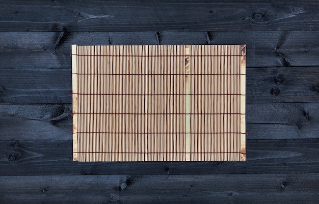 Photo bamboo mat on wooden table, top view