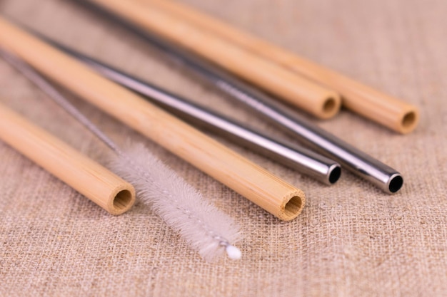 Bamboo and metal reusable straws on a natural linen background. Ecological bamboo straws.