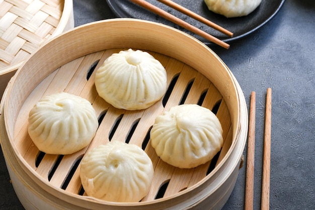 Bamboo steamers with tasty baozi dumplings chopsticks and bowl of sauce