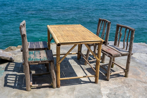 Bamboo table and wooden chairs in empty cafe next to sea water in tropical beach Island Koh Phangan Thailand