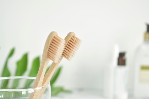 Bamboo toothbrushes are eco-friendly in a glass with a copy of the space on a marble-white background. Zero waste. Free plastic.