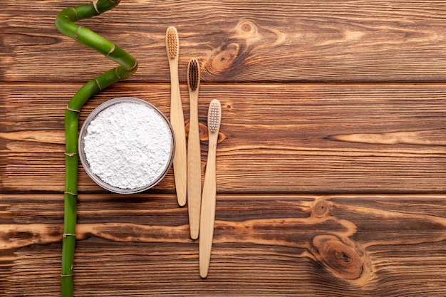 Bamboo toothbrushes, bamboo plant, dentifrice tooth powder on wooden background. Flat lay copy space. Biodegradable natural bamboo toothbrush. Eco friendly, Zero waste,Dental care Plastic free concept