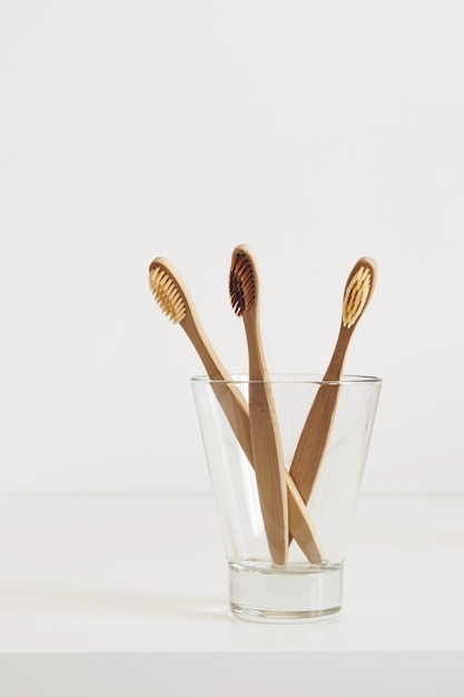 Bamboo toothbrushes with natural bristles in glass in Scandinavian style bathroom.