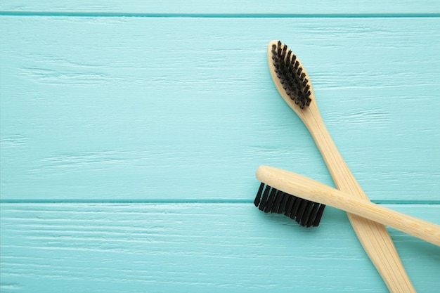 Bamboo wood toothbrush with black brush bristles on blue wooden background