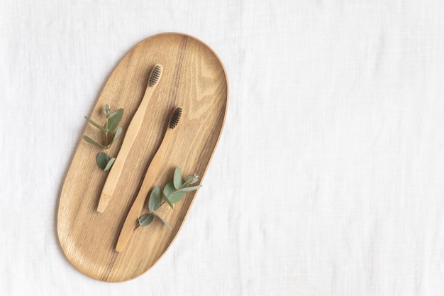 Bambool toothbrush and leaves of eucalyptus on a wooden plate