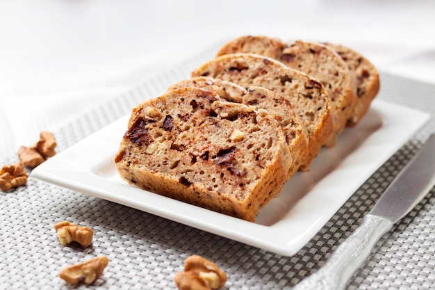 Banana cake with walnuts and dark chocolate on a white square plate