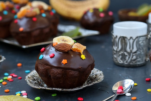 Banana-chocolate muffins, covered with icing and confectionery confetti