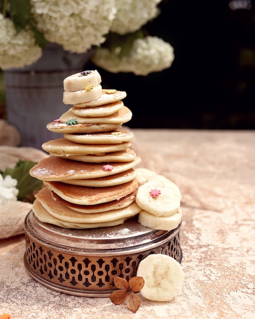 Banana pancake with pieces of fruit and spring flowers. Vintage tray and vase