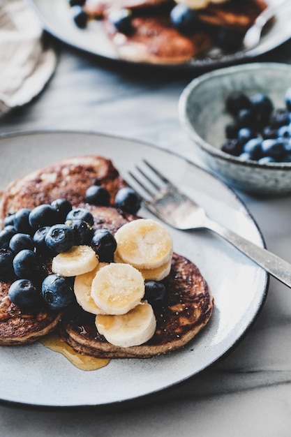 Banana pancakes with bluelerry and honey over marble table