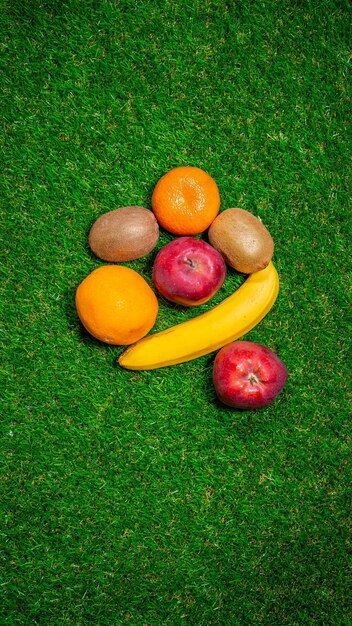 Banana red apple and different fruits laying on grass flat lay Space for text