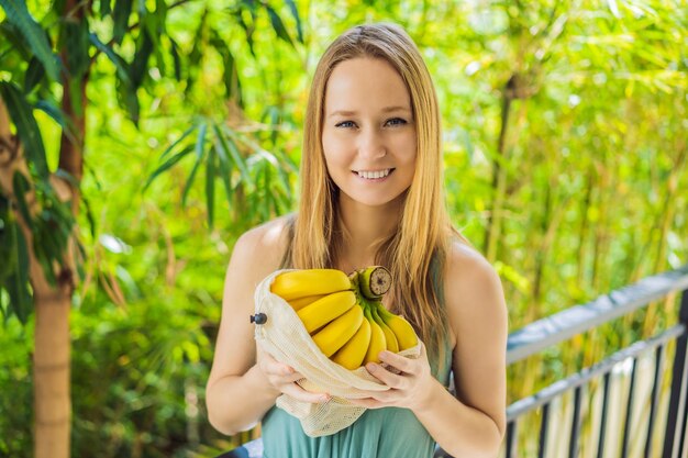 Banana in a reusable bag in the hands of a young woman Zero waste concept plastic free concept Healthy clean eating diet and detox Summer fruits