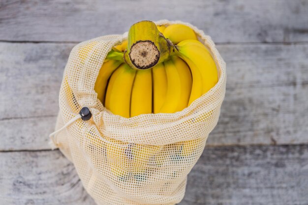 Banana in a reusable bag on a stylish wooden kitchen surface Zero waste concept plastic free concept Healthy clean eating diet and detox Summer fruits